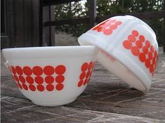 two red and white bowls sitting on top of a wooden table next to each other