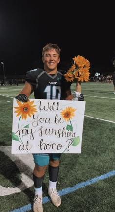 a man holding a sign that says will you be my sunshineflower at proco?