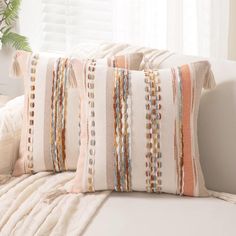 a white couch with two pillows on it and a plant in the window sill