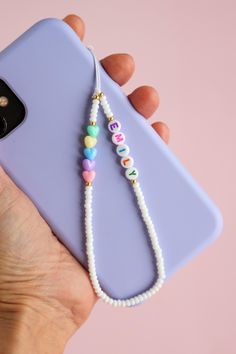 a person holding a cell phone with beads on it