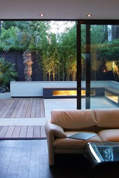 a living room filled with furniture next to a glass wall and wooden floored area