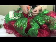 someone decorating a christmas wreath with green and red mesh