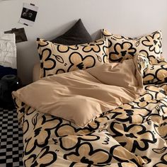 an unmade bed with black and gold sheets