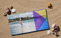 an open book sitting on top of a sandy beach next to shells and seashells