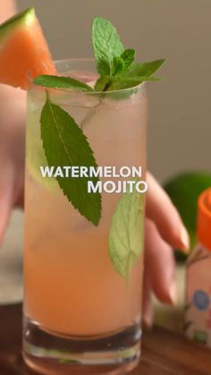 a hand holding a glass filled with watermelon mojito next to a jar of yogurt