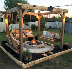 a fire pit in the middle of a yard with swings and lights on it's sides