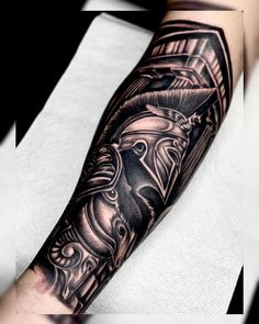 a man's arm with a black and grey tattoo design on the left forearm