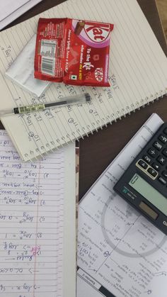 a calculator, notebooks, and pen on a desk with writing paper