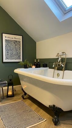 a white bath tub sitting under a skylight next to a bathroom rug and sink