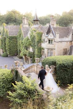 a bride and groom walking up the stairs to their wedding venue in an english country house