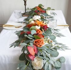 a long table with white and orange flowers on it, candlesticks are in the background