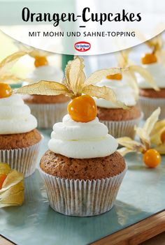 orange cupcakes with white frosting and cherries on top, sitting on a tray