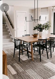 a dining room table with black chairs and a potted plant on top of it