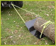 a log being pulled by a chainsaw in the grass with a vehicle behind it