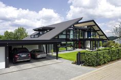 two cars are parked in front of a large house with an attached carportion