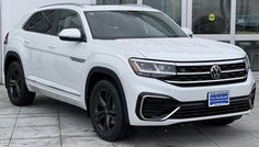 a white volkswagen atlas parked in front of a building