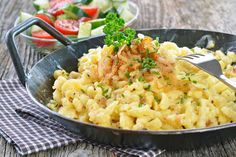 a bowl filled with macaroni and cheese on top of a table next to salad