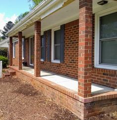 a red brick house with white trim on the front porch and side steps leading up to it