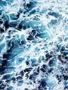 an aerial view of the ocean waves with blue and white colors, taken from above