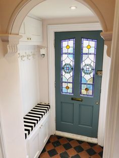 a blue door with two stained glass windows and a black and white checkered bench