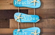 two blue flip flops are hanging on a wooden wall with the words beach vibes painted on them