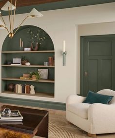 a living room with green painted walls and white furniture in the center, along with bookshelves