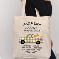 a woman holding a tote bag with farmers market on it