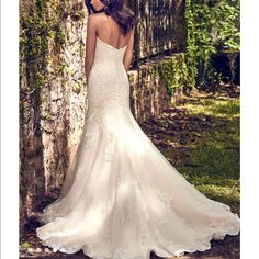 a woman in a wedding dress standing next to a stone wall with ivy growing on it