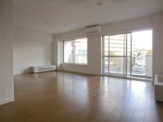 an empty living room with hard wood flooring and sliding glass doors to the balcony