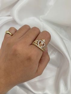 a woman's hand wearing a gold ring with two diamonds on it and a white satin background