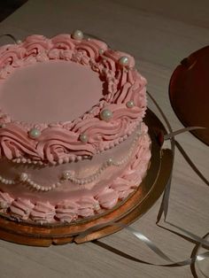 a pink cake sitting on top of a wooden table next to a red heart shaped object