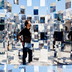 a man standing in front of a mirror wall with multiple mirrors on it's sides