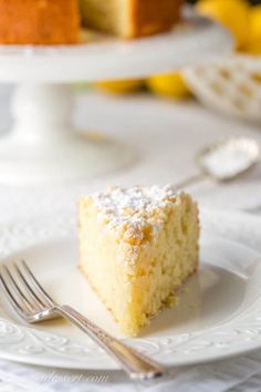 a piece of cake on a white plate with a fork and lemons in the background