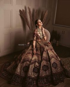 a woman sitting on top of a chair wearing a dress with feathers in her hair