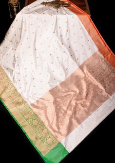 Embrace the spirit of patriotism and elegance with our Tricolor saree, meticulously crafted in pure silk. This exquisite garment beautifully showcases the tricolor palette of saffron, white, and green, and a blouse piece in Blue, symbolizing India's rich cultural heritage and national pride. The zari also features exquisite zari work blending luxurious silk with the iconic symbolism of our beloved nation SILK MARK CERTIFIED This saree is ready to wear with fall and pico done. Handmade silk tassels adorn the pallu and add more grace to it. An unstitched blouse fabric is included. *Note: There may be minor variations in the shade, the texture of the product. Hues/textures show differently due to variations in screen settings and other factors, *Note: This is a handwoven saree and there may b Tricolor Palette, House Of Blouse, Silk Tassels, Katan Silk Saree, Sarees Silk, Katan Silk, Zari Work, Banarasi Sarees, Cultural Heritage