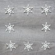 several white snowflakes are arranged on a wooden surface, one is in the shape of a star