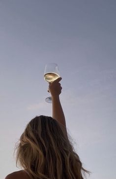 a woman holding up a wine glass in the air