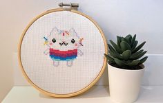 a small potted plant sitting next to a cross stitched animal