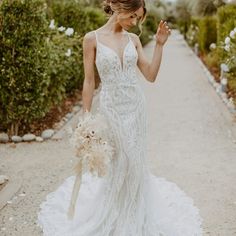 a woman in a wedding dress is walking down the road with her hand on her hip