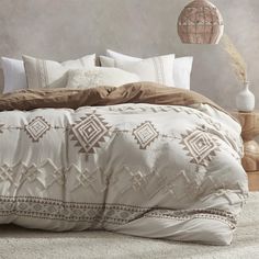 a bed with white and brown comforters in a room next to a lamp on a table