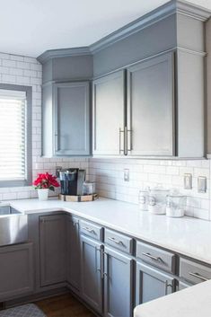 a kitchen with gray cabinets and white counter tops