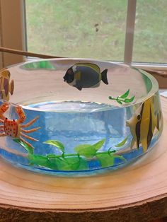 a glass bowl with fish and sea animals in it sitting on top of a wooden table