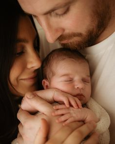 a man and woman holding a baby in their arms