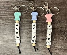 three keychains with nurses written on them sitting on top of a wooden table