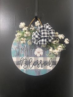 a door hanger that says simply blessed with cotton flowers and a bow on it