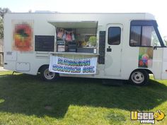 an ice cream truck is parked in the grass with its door open and food on display