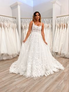 a woman is standing in front of some wedding dresses