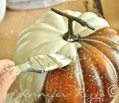 a person painting a pumpkin with a brush