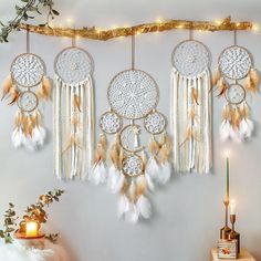 there are many dream catchers hanging on the wall next to a table with candles