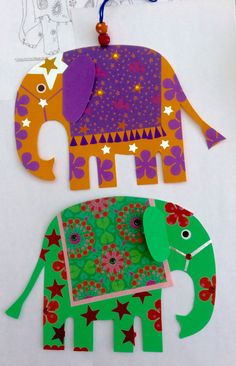 two paper cut out elephants on top of a piece of paper with flowers and stars